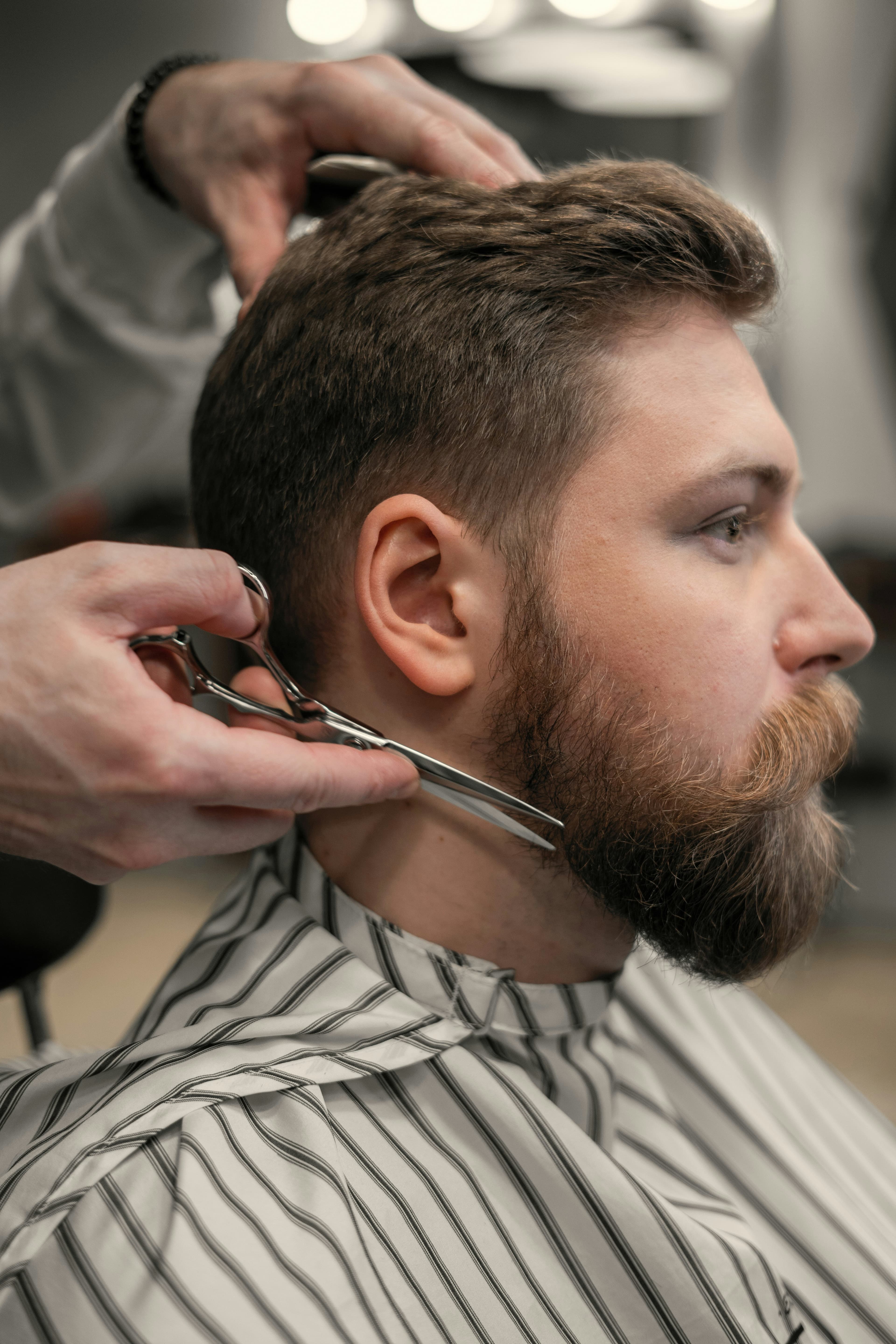Barbero recortando una barba con tijera